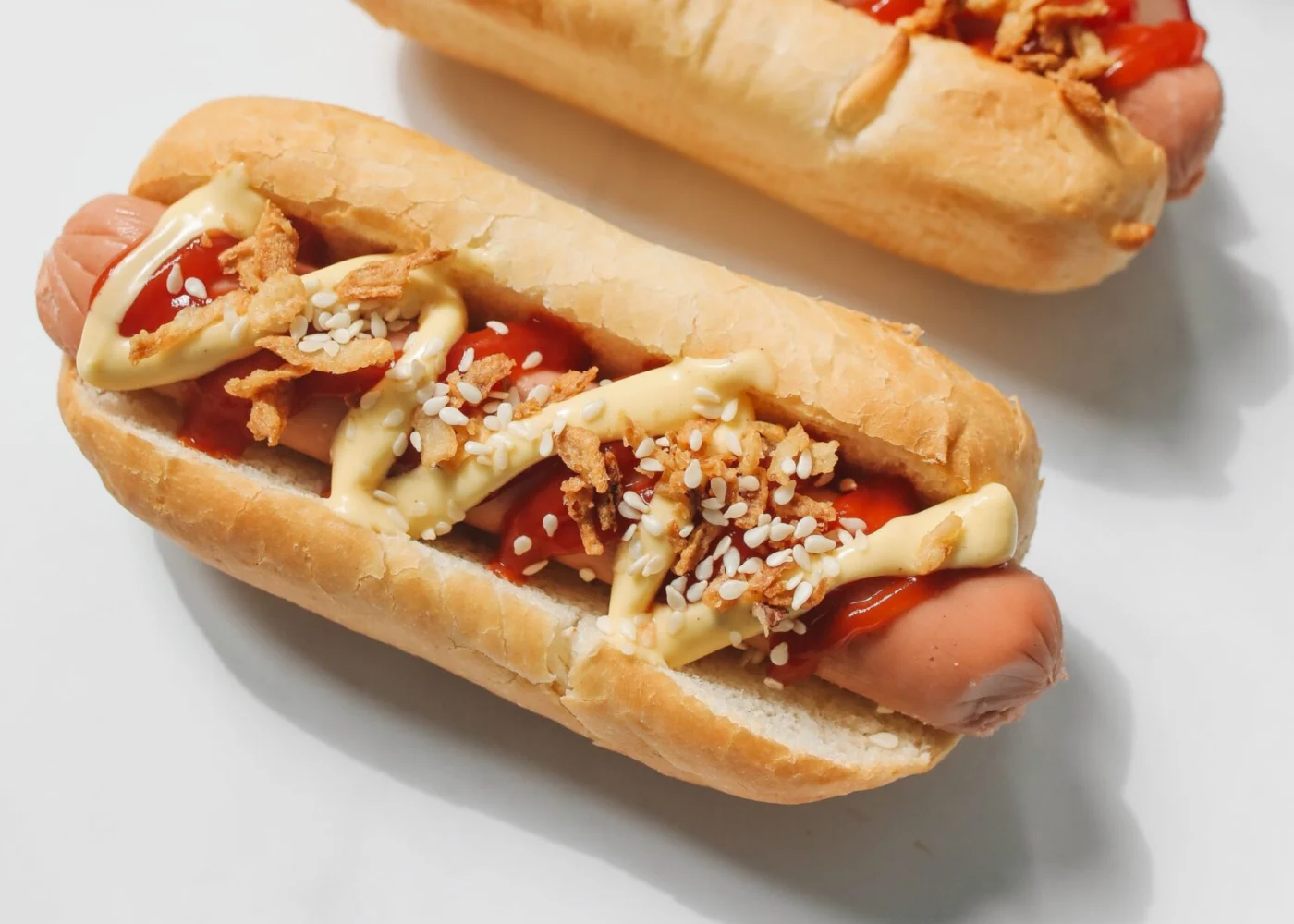 Hot dogs with sauces, crispy onions, sesame seeds, and radish